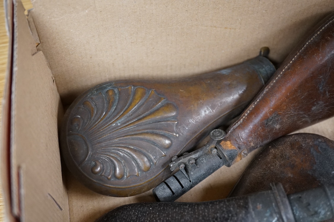Three gun-sized copper powder flasks, two of which are embossed, together with four leather shot bags each with sprung chargers, two iron and two brass examples, one of which is embossed with a hunting scene (7)